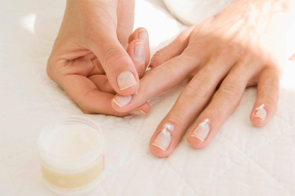Una mujer aplicándose crema hidratante en las cutículas.