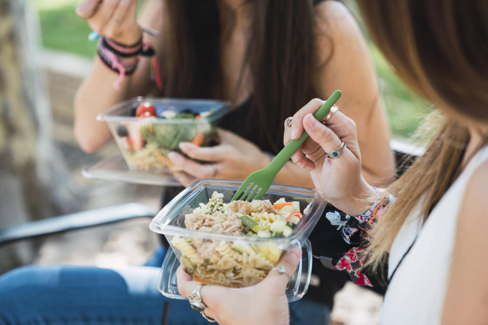 personas que comen ensalada en un recipiente de plástico