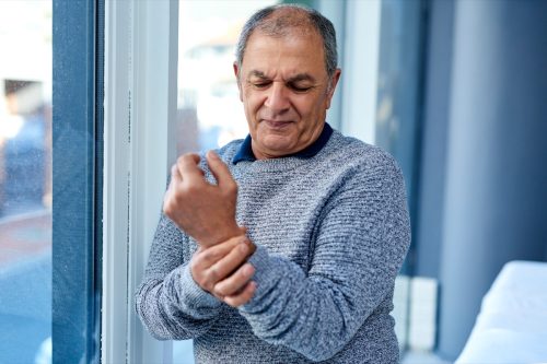Foto de un hombre mayor con dolor en el brazo.
