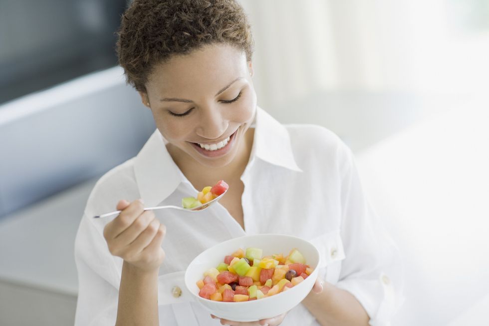 Una mujer comiendo una ensalada de frutas.