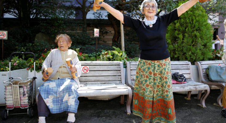 Natsu Naruse, 100 year-old, and other partcipants exercise with wooden dumbbells during a health promotion event to mark J...