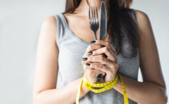 Woman holding a knife and for with hands tied together with a tape measure