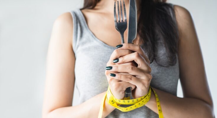 Woman holding a knife and for with hands tied together with a tape measure