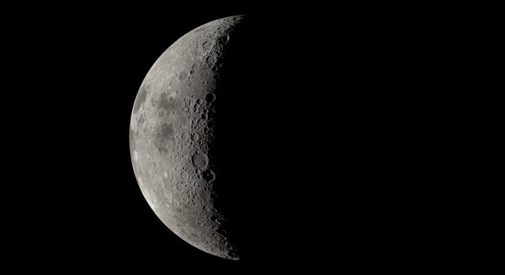A large sphere is prominent in the center of the image. It is pockmarked with indentations and is generally grey, with patches of dark.