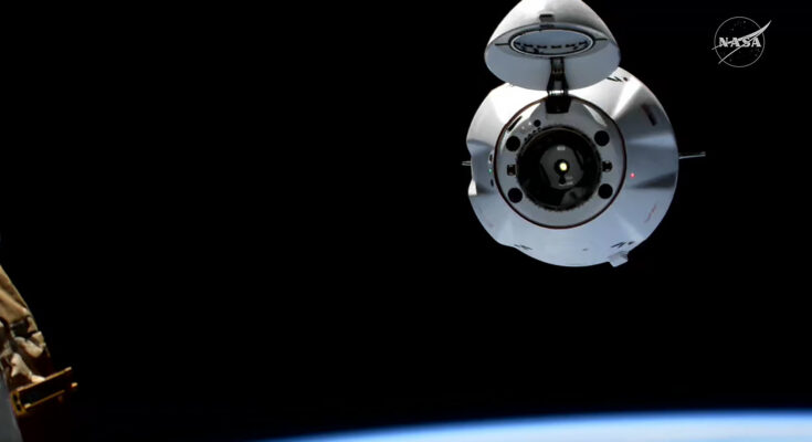 The SpaceX Dragon cargo spaceraft, with its nosecone open, approaches the International Space Station for an automated docking.