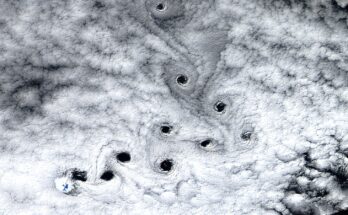 A satellite photo sowing ten dark holes in the clouds swirling in the sky