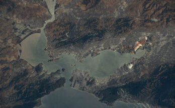 California's San Francisco Bay Area as seen from the International Space Station orbiting 260 miles above. The water is slate gray, while the surrounding land is in shades of brown, deep green, and gray.