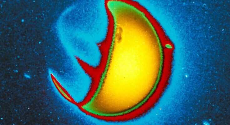 A false-color, close-up image of Earth’s exosphere as captured by the Carruthers Geocorona Observatory against a dark blue background. The image shows a semicircle glowing yellow and outlined in red.