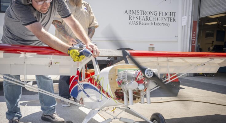 One man manages engine speed with a hand-held controller, while another firmly holds the subscale aircraft in place.