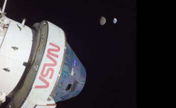 A large white space shuttle labeled in red "NASA" is seen in the darkness of space.
