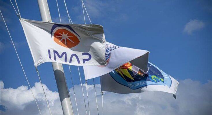 Flags for NASA’s IMAP (Interstellar Mapping and Acceleration Probe) mission and its two rideshares, NASA’s exosphere-studying Carruthers Geocorona Observatory and National Oceanic and Atmospheric Administration’s (NOAA) Space Weather Follow On–Lagrange 1 (SWFO-L1) spacecraft fly outside Astrotech Space Operations Facility near NASA’s Kennedy Space Center in Florida.