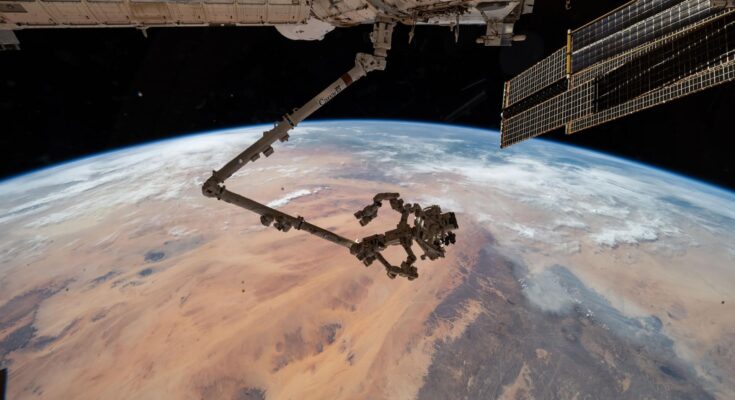 The International Space Station's 57.7-foot-long robotic arm, Canadarm2, with its fine-tuned robotic hand, Dextre, attached is pictured extending from the International Space Station's Harmony module. The orbital outpost was soaring 260 miles above the Saharan Desert in Libya at the time of this photograph.