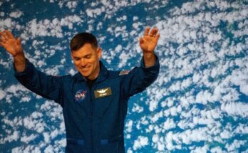 a man in blue jumpsuit raises his arms