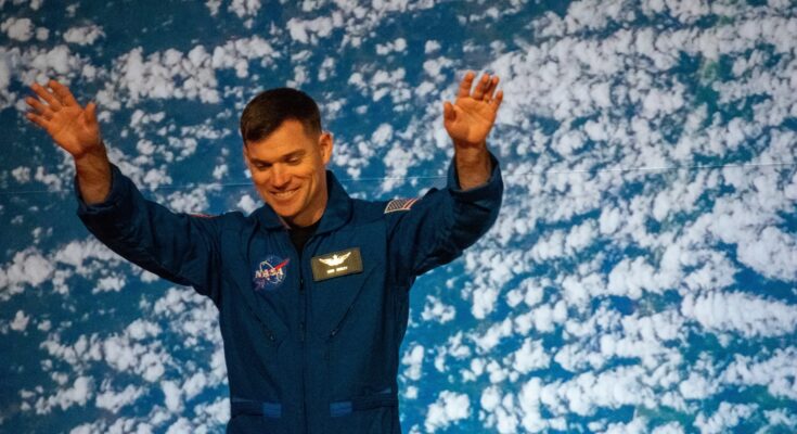 a man in blue jumpsuit raises his arms