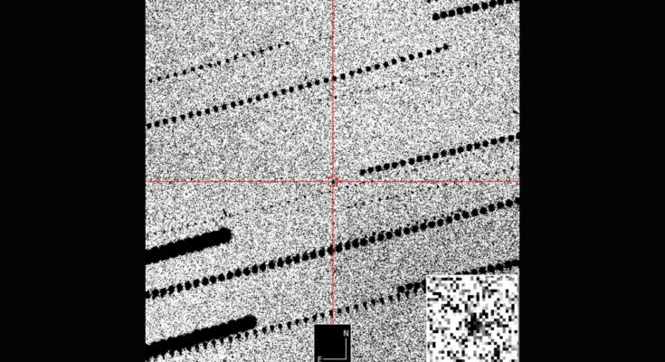 A gray grainy image with a red cross hair in the middle zooming in on a black dot against the grains