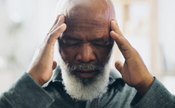 Older age man with hands placed on temples