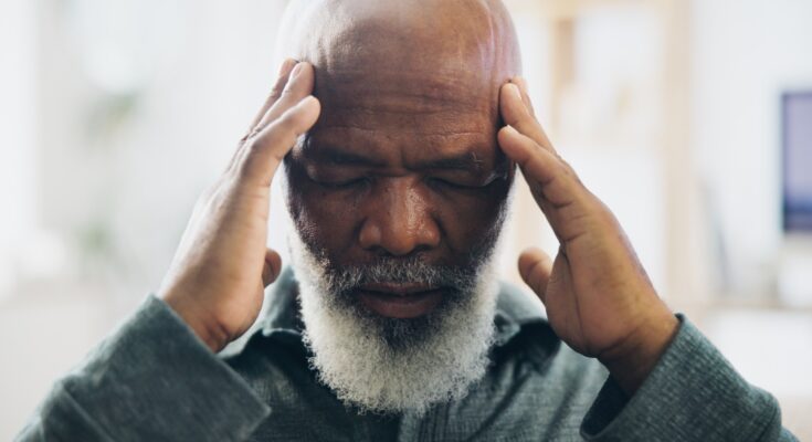 Older age man with hands placed on temples