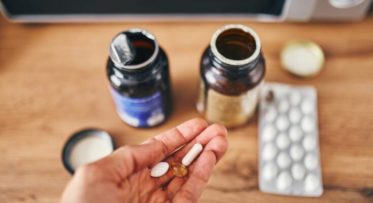 Pouring vitamins on one hand from a bottle