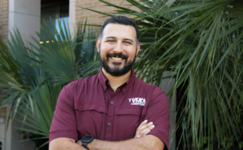 a man in a maroon shirt stands in an outdoor setting