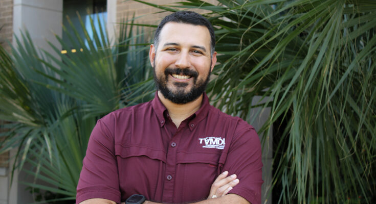 a man in a maroon shirt stands in an outdoor setting