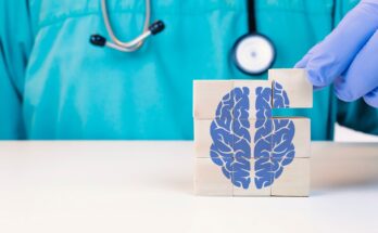 Doctor gloved hand stacking wooden blocks to form a square cube with a blue brain image on them