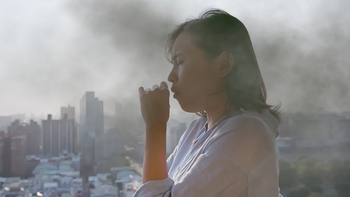 una mujer tose en aire contaminado
