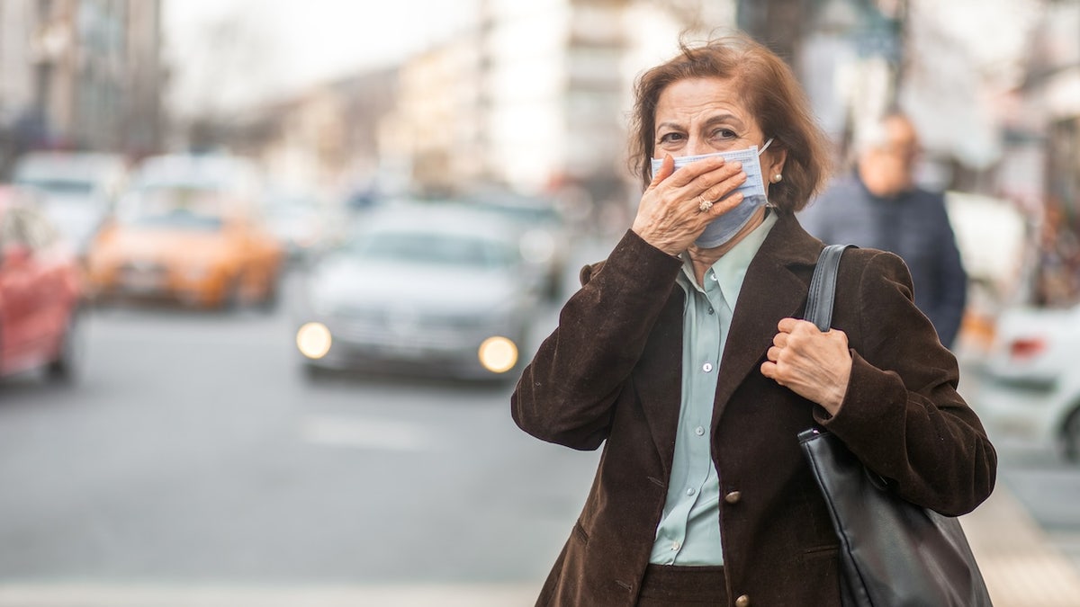 Una mujer en una calle de la ciudad con una máscara.