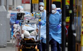 Medical workers move a patient between ambulances during the COVID pandemic. Pic: Reuters