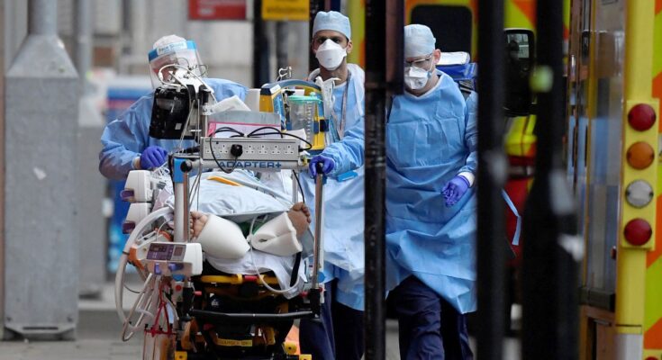 Medical workers move a patient between ambulances during the COVID pandemic. Pic: Reuters