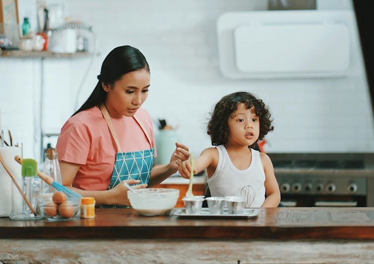 Una mujer horneando con un niño en la cocina.